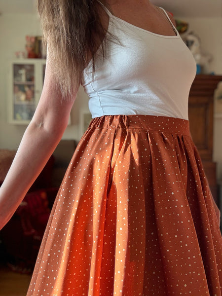 Vid kjol i tegelfärgad bomull med guldprickar