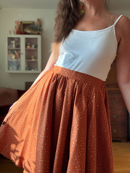 Vid kjol i tegelfärgad bomull med guldprickar