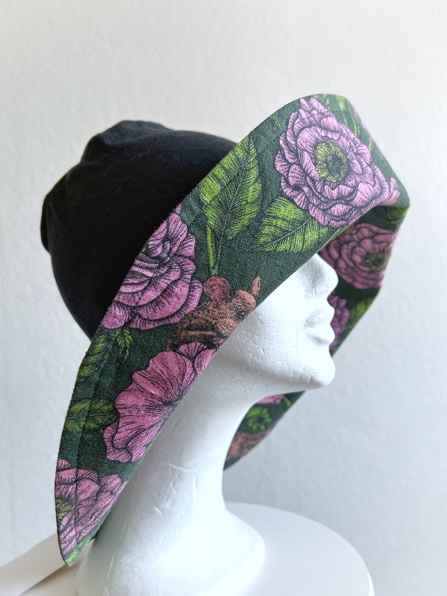 Solhatt i svart linne med rosa blommor