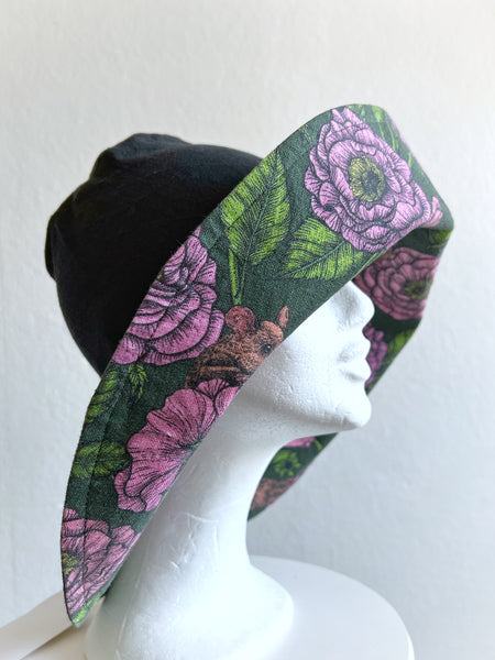 Solhatt i svart linne med rosa blommor